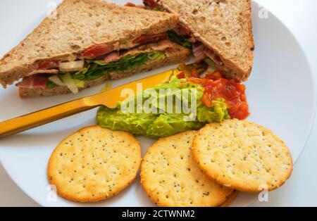 BLT, bacon, laitue et sandwich à la tomate sur du pain brun avec guacamole et salsa et craquelins Banque D'Images