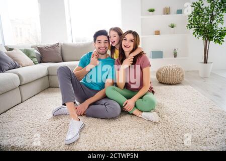 Photo de tout le corps de la famille positive papa maman fille enfant asseyez-vous tapis de tapis embrasse le soutien doux dans la maison à l'intérieur Banque D'Images