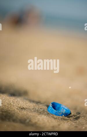 Plastique bouchon à vis d'une bouteille abandonnée sur une plage de sable. Banque D'Images