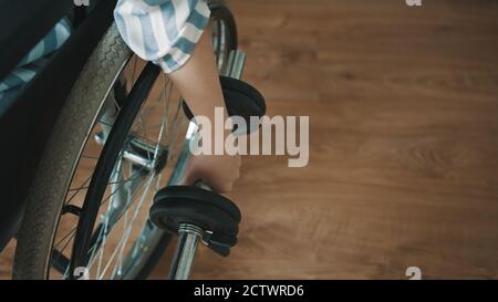 Gros plan d'une jeune femme qui lève des poids tout en étant assise dans un fauteuil roulant. Photo de haute qualité Banque D'Images