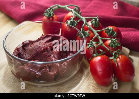 Produits siciliens: Un bol de sauce tomate concentrée appelé 'astratto', à côté d'un bouquet de tomates Piccadilly. Banque D'Images