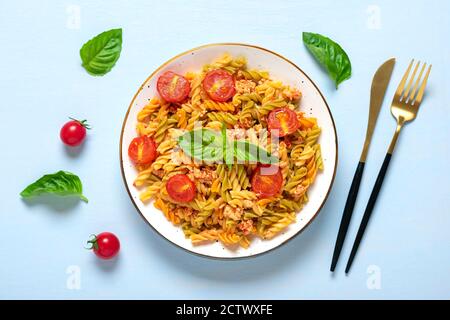 Fusilli - pâtes italiennes classiques de blé dur avec viande de poulet, tomates cerises, basilic dans une sauce tomate dans un bol blanc sur une table en bois bleu Banque D'Images