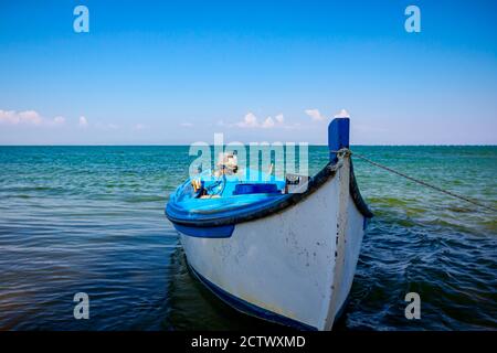 Arc d'un petit bateau de pêche en bois attaché avec une corde flottant sur une surface d'eau tranquille. Banque D'Images