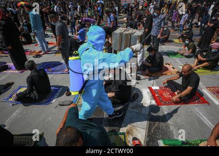 25 septembre 2020, Irak, Sadr City: Un travailleur en costume de protection vaporise du désinfectant sur les musulmans pendant les prières du vendredi après des mois de suspension en raison de la propagation de la pandémie du coronavirus (COVID-19). Photo: Ameer Al Mohammaw/dpa Banque D'Images