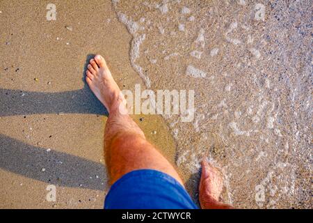 Les touristes pieds nus apprécient la promenade paisible, la détente sur la plage de sable, la marche à travers les eaux peu profondes. Banque D'Images