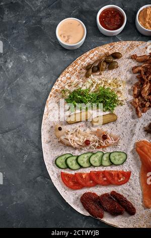 Shawarma maison, burrito, poulet et saumon roulés avec des légumes et de la sauce. Vue de dessus des ingrédients avec espace libre. Banque D'Images
