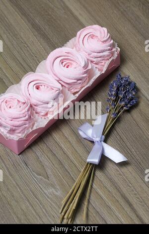 zephyr rose dans une boîte cadeau. Un bouquet de lavande se trouve à proximité. Banque D'Images