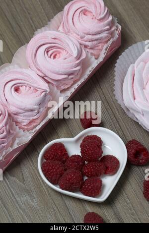 Guimauve rose dans une boîte cadeau. Un bouquet de framboises se trouve à proximité. Banque D'Images