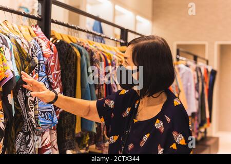 Femme âgée avec masque facial pour faire du shopping dans le grand magasin. Banque D'Images