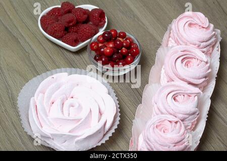 Guimauve rose dans une boîte cadeau. À proximité se trouve un bouquet de canneberges et de framboises. Banque D'Images