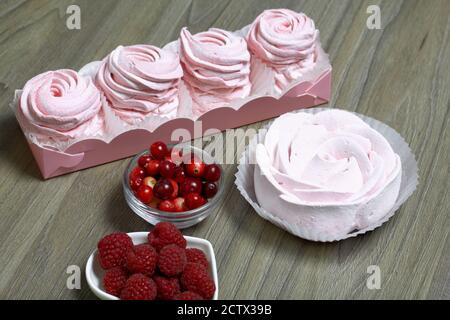 Guimauve rose dans une boîte cadeau. À proximité se trouve un bouquet de canneberges et de framboises. Banque D'Images