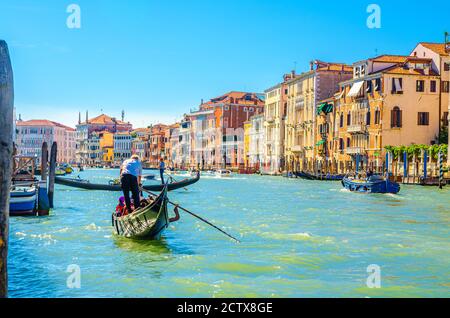 Venise, Italie, 13 septembre 2019 : gondolier et touristes en gondole bateau traditionnel naviguant sur l'eau du Grand Canal avec architecture vénitienne typique bâtiments colorés arrière-plan Banque D'Images