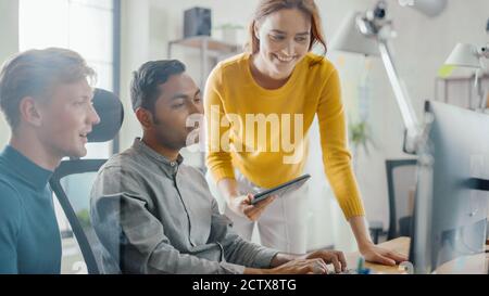 Entrepreneur talentueux travaillant sur son ordinateur de bureau avec le chef de projet et le chef d'équipe debout à côté de lui, ayez la discussion, trouver le problème Banque D'Images