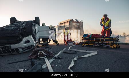 Les ambulanciers paramédicaux et les pompiers arrivent sur la scène des accidents de la route. Professionnels de secours la victime blessée piégée dans le véhicule en retournement par Banque D'Images