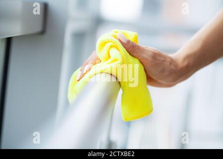 Une femme de nettoyage professionnelle nettoie la table à l'aide d'une éponge et d'un spray Banque D'Images