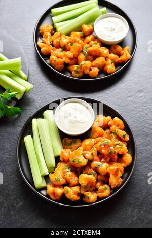 Ailes de buffle de chou-fleur avec céleri et sauce sur plaque sur fond de pierre noire. Alimentation saine, concept de nourriture à base de plantes. Banque D'Images