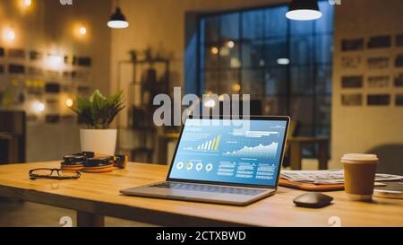 L'ordinateur portable du bureau affiche les données de croissance de l'entreprise avec des graphiques, des graphiques et une interface utilisateur logicielle. En arrière-plan élégant et moderne Office Studio dans le Banque D'Images