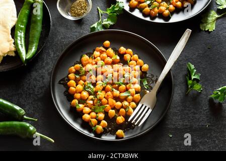 Pois chiches grillés croustillants de style indien sur une assiette sur fond de pierre noire. Concept végétarien végétalien. Banque D'Images