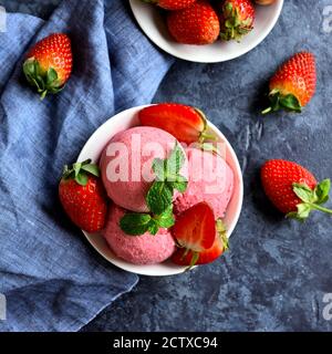 Pelle à glace aux fraises avec fraises fraîches dans un bol sur fond de pierre bleue. Délicieux dessert froid d'été. Vue sur le dessus, plat Banque D'Images