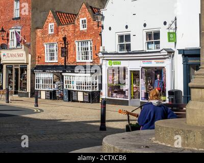 Busker sur le marché, traversez les marches et le plus ancien chimiste Faites vos courses en Angleterre dans le Market place Knaresborough North Yorkshire Angleterre Banque D'Images