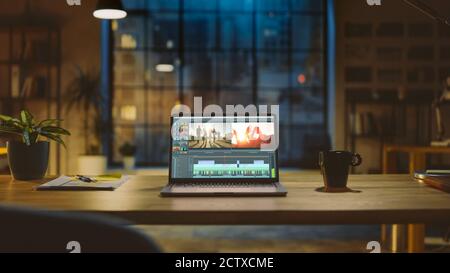 Prise de vue d'un ordinateur portable debout sur un bureau avec un logiciel de montage vidéo professionnel. À l'arrière-plan, lumière chaude en soirée et espace ouvert Banque D'Images