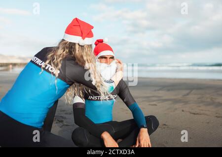 Couple sur la plage s'aider les uns les autres pour s'habiller Comme le Père Noël Banque D'Images