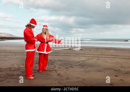 Un couple habillé comme le père noël sur la plage Banque D'Images