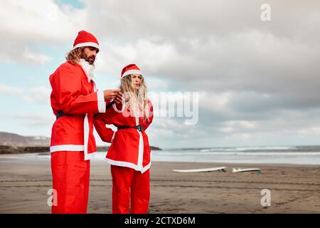 Un couple habillé comme le père noël sur la plage Banque D'Images