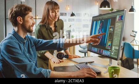 La directrice artistique féminine consulte un collègue concepteur, elle travaille sur un portrait dans le logiciel d'édition de photos. Ils travaillent dans un loft Cool Office. Ils ont l'air très Banque D'Images