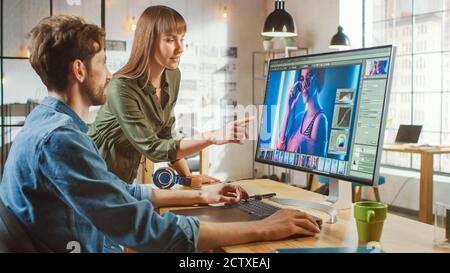 La directrice artistique féminine consulte un collègue concepteur, elle travaille sur un portrait dans le logiciel d'édition de photos. Ils travaillent dans un loft Cool Office. Ils ont l'air très Banque D'Images