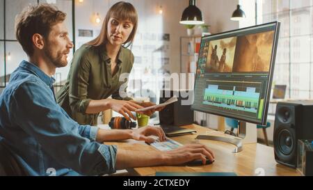 Belle femme directrice d'art consulte beau collègue de Video Editor, ils travaillent sur un projet vidéo sur les astronautes. Ils travaillent dans un loft Cool Office Banque D'Images