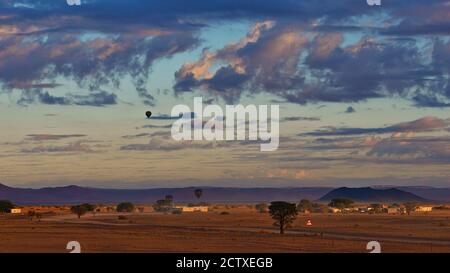 Des ballons à air chaud se détachent pour une aventure avant le coucher du soleil dans le désert du Namib près de Sesriem, Namibie, Afrique avec un beau ciel nuageux. Banque D'Images