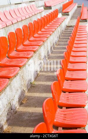 Sièges en plastique vides rouges d'un petit stade. Arrière-plan vertical Banque D'Images