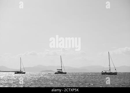 Trois bateaux à voile dans la mer près de l'île d'Aegina, Grèce. Photographie en noir et blanc, paysage marin Banque D'Images