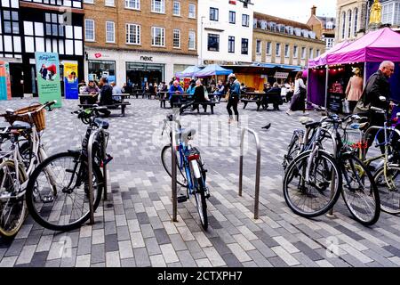 Personnes assises sur des bancs en train de manger à la place du marché de Kingston, avec des vélos garés Banque D'Images