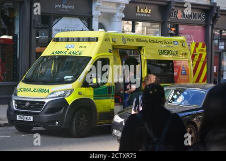 Service d'ambulance des West Midlands sur Colmore Row à Birmingham, traitant un homme détenu par la police pour violence Banque D'Images