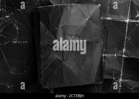 Noir sur noir. Papier vierge froissé rectangle sur fond froissé texturé, vue de dessus avec espace de copie pour le texte. Banque D'Images