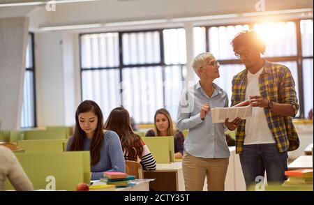 Un étudiant de sexe masculin dans la classe universitaire pose des questions sur le leçon à une femme professeur Banque D'Images