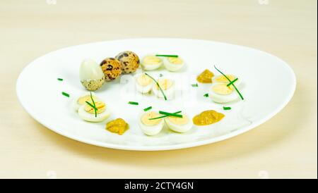 œufs de caille bouillis avec moutarde et ciboulette sur une assiette Banque D'Images