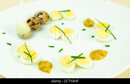 œufs de caille bouillis avec moutarde et ciboulette sur une assiette Banque D'Images