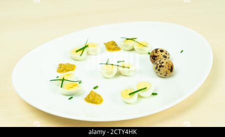 œufs de caille bouillis avec moutarde et ciboulette sur une assiette Banque D'Images