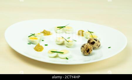 œufs de caille bouillis avec moutarde et ciboulette sur une assiette Banque D'Images