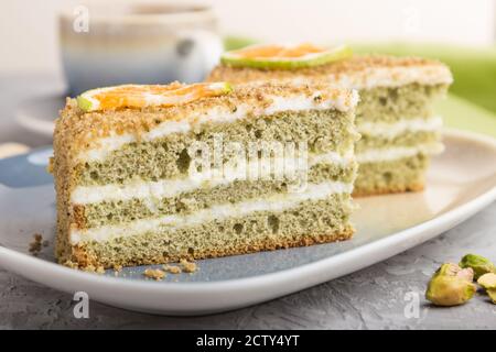 Gâteau maison avec crème au lait et pistache avec tasse de café sur fond de béton gris et textile vert. Vue latérale, gros plan, mise au point sélective Banque D'Images