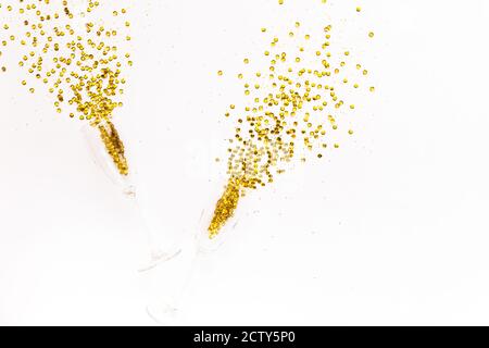 Verres à champagne avec guirlande de confettis dorée sur fond blanc. Flat Lay, vue de dessus Célébrez le concept de fête. Banque D'Images