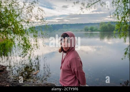 une jeune femme dans un chandail se tient au bord du lac Banque D'Images