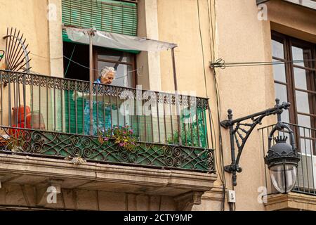 Barcelone, Espagne 05/01/2010: Une femme caucasienne âgée aux cheveux gris est debout dans le petit balcon de son appartement. L'appartement est dans un très vieux buil Banque D'Images