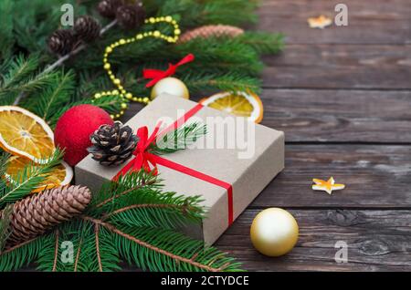 Composition de Noël ou du nouvel an. Boîte cadeau avec branches, cônes et décorations en sapin sur fond de bois vintage. Gros plan, mise au point sélective Banque D'Images