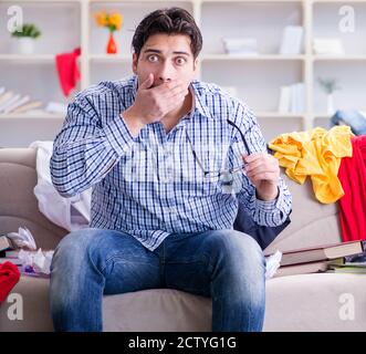 Le jeune homme travaillant dans l'étude de la chambre en désordre Banque D'Images