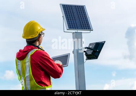 Un technicien asiatique vérifie la maintenance des panneaux solaires, le poteau d'éclairage extérieur avec de l'énergie de petit panneau solaire par themself est nouvelle technologie et de l'ener Banque D'Images