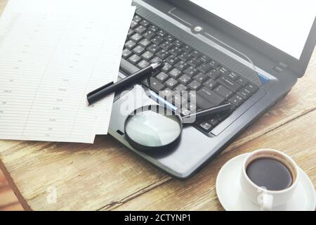 Bureau avec ordinateur portable, papiers et loupe sur table en bois Banque D'Images